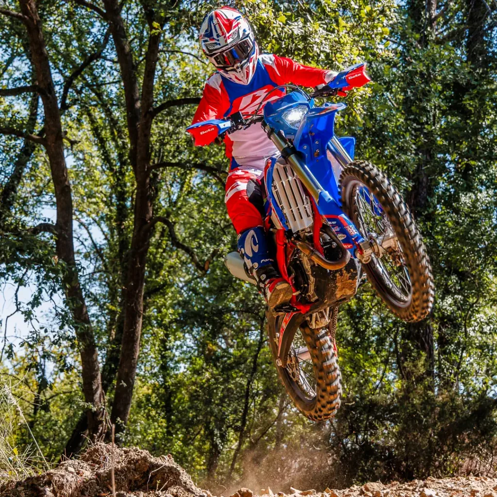 2027 Beta RR Race 4-Strokes First Look: Jumping a motorcycle in the forest.