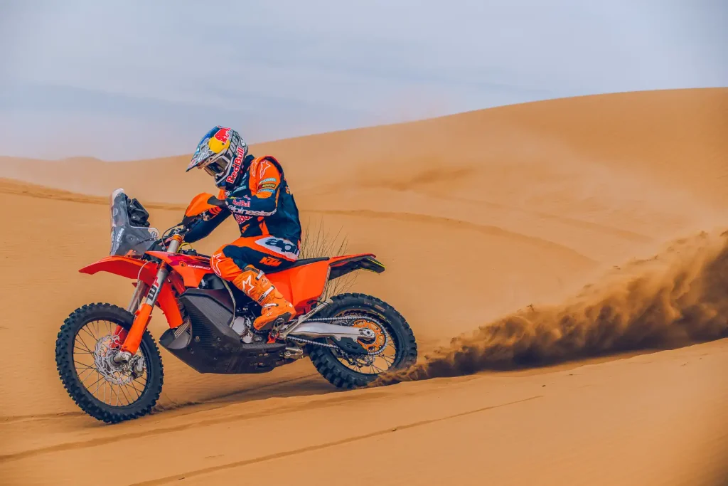 Luciano Benevides pitching his dirt bike sideways in the sand while roosting