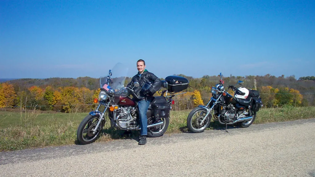 Jesse Ilminen poses with his Honda CX500 with fall colors behind him.