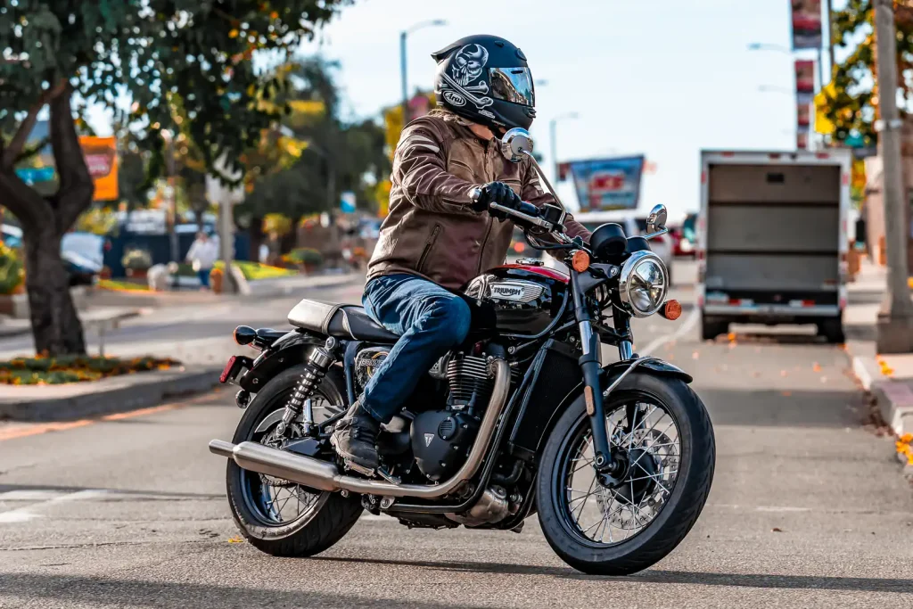 2026 Triumph Bonneville T100 making a left hand turn in an urban area.