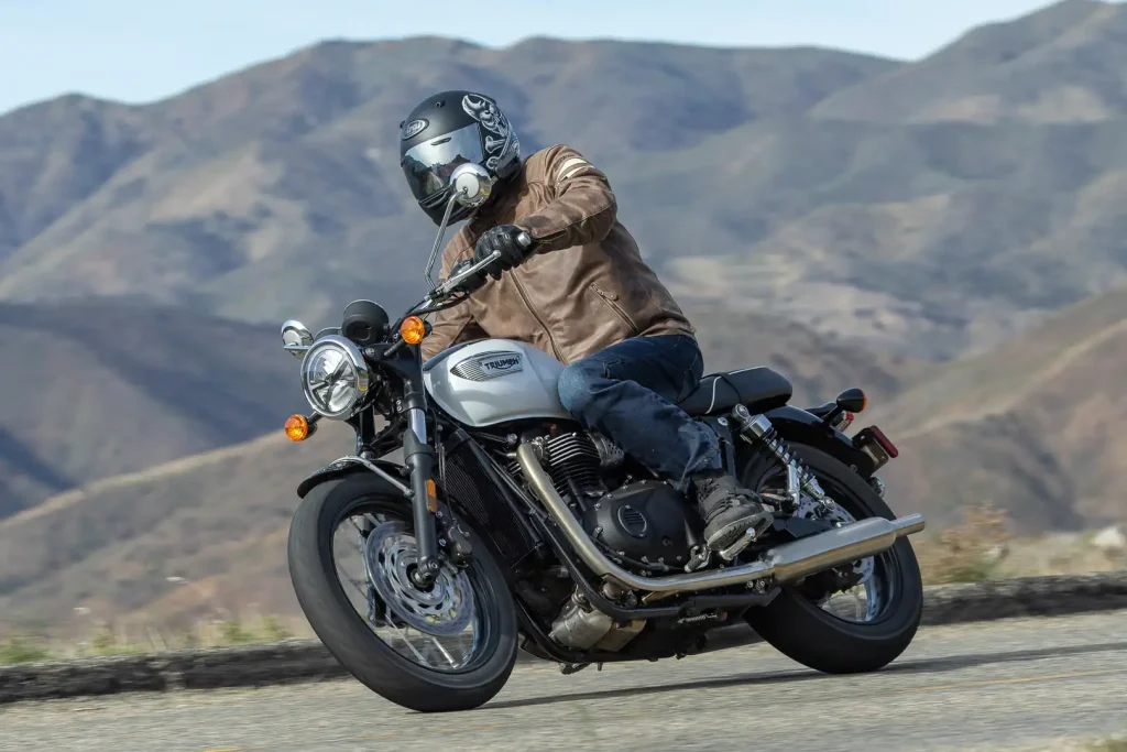 The 2026 Triumph Bonneville T100 leaning to the right on a mountain road.