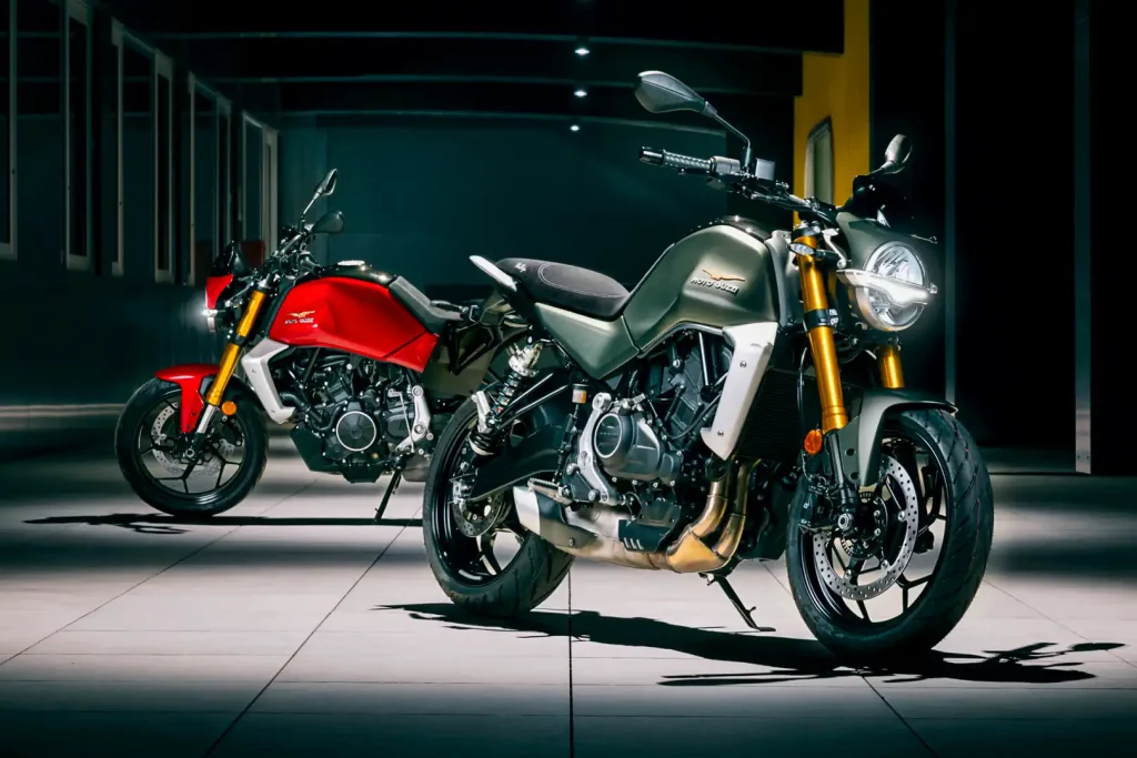 Two 2027 Moto Guzzi The Trip motorcycles. Left profile of one. Right 3/4 front view of other